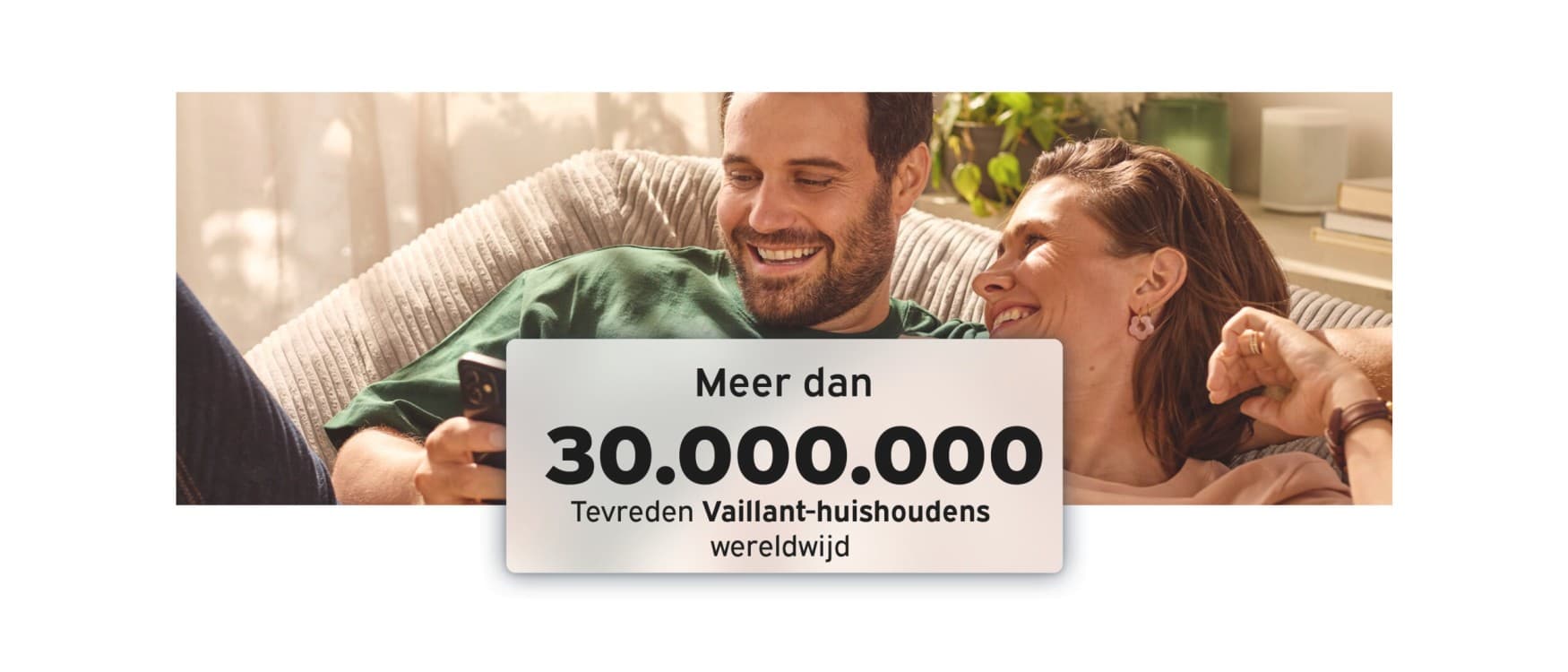 Stel zit comfortabel binnen, glimlacht en kijkt naar hun telefoon
