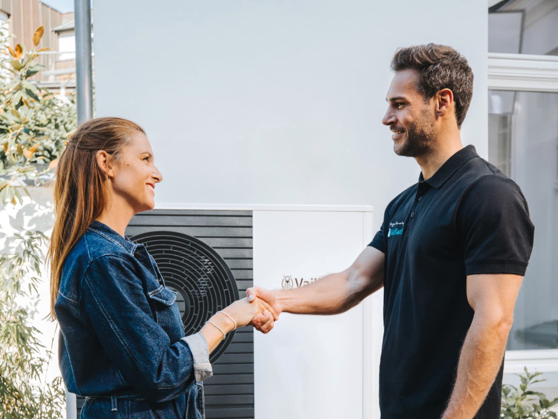 Een installateur die een vrouw de hand schudt voor een warmtepomp