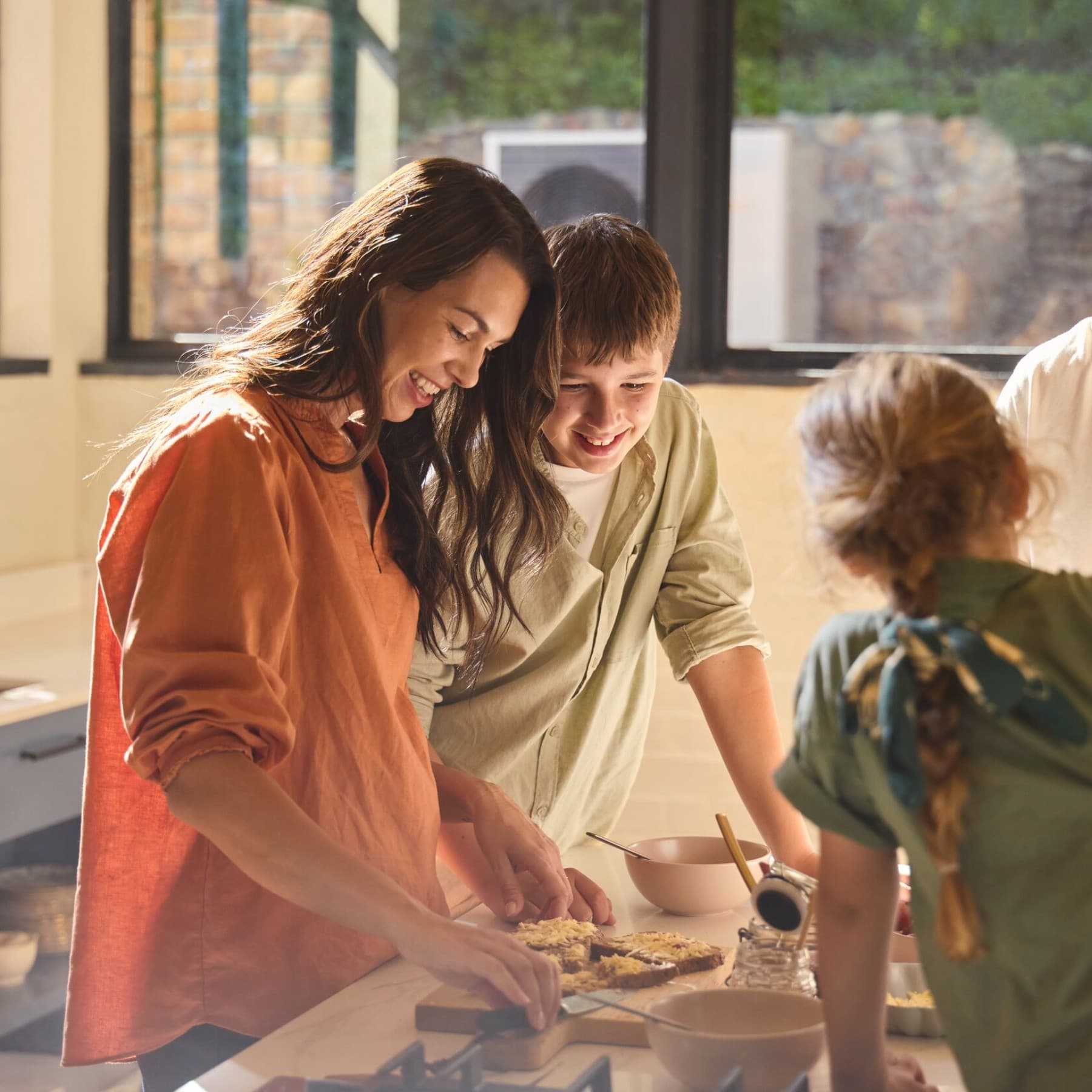 Familie bereidt eten in de keuken met een warmtepomp buiten in de tuin