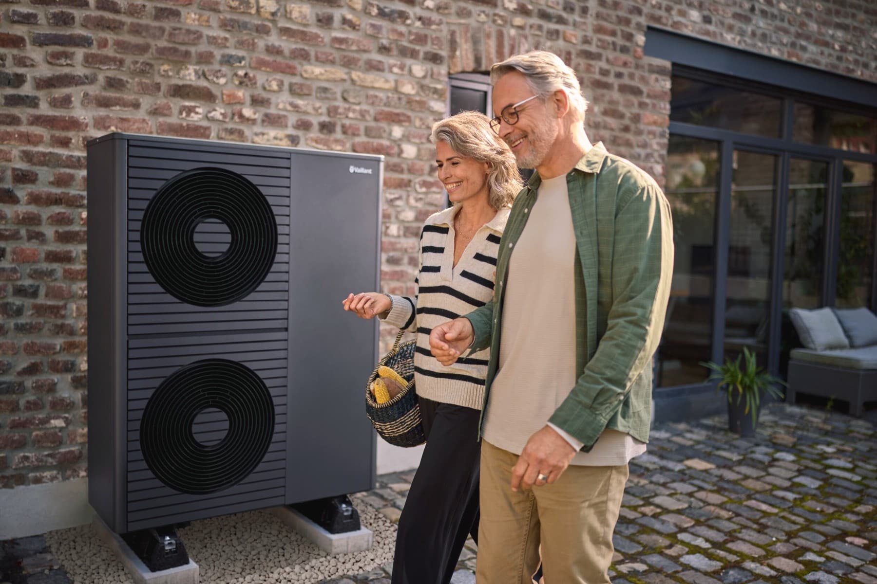 Een echtpaar loopt buiten hun huis voor een warmtepomp.