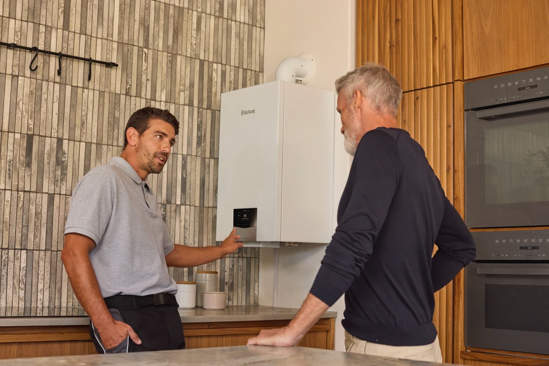 Installateur en huiseigenaar staan voor de boiler